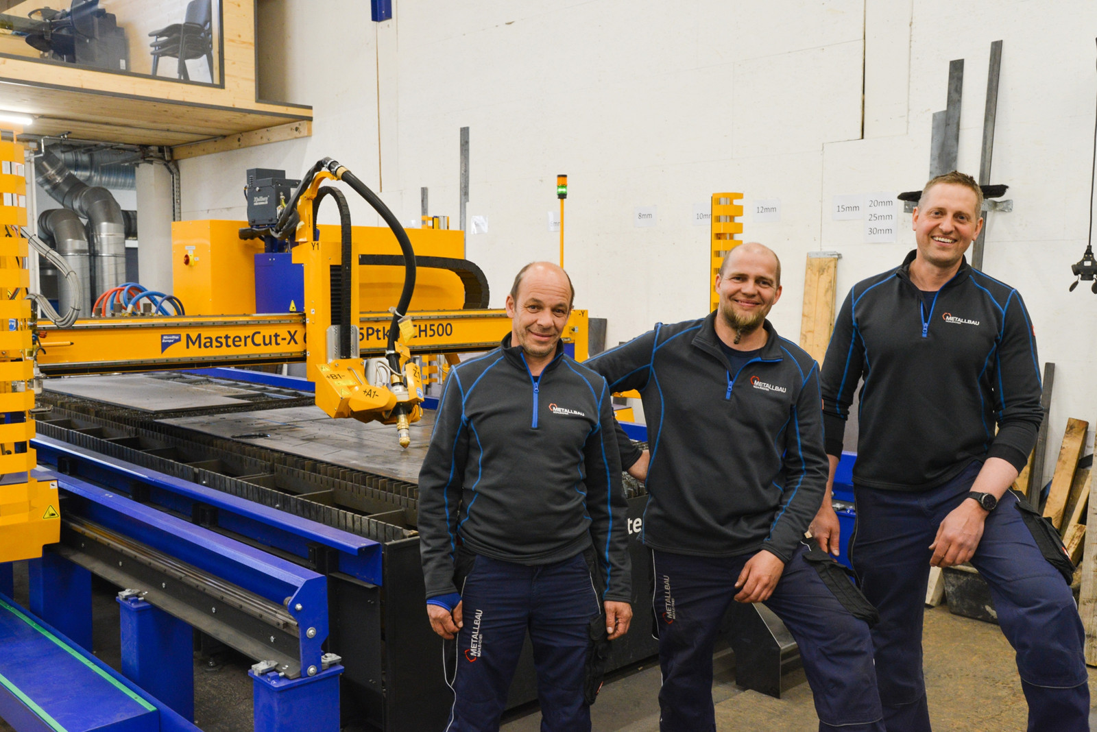 Geschäftsführer Robert Mühlbacher (von rechts), Maschinenbediener Patrick Muigg und Techniker Gottfried Leitner sind hochzufrieden mit der seit Juli 2021 im Einsatz befindlichen automatisierten Schneidlösung im eigenen Haus. 