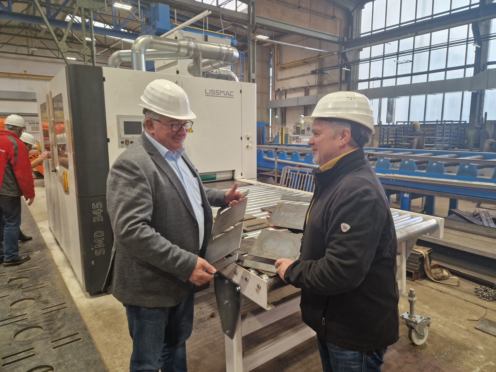 Roland Möbius, zuständig für den Bereich Zuschnitt in der Brückenwerkstatt Dresden und Dirk Schürstedt, Gebietsverkaufsleiter Metal Processing bei Lissmac, prüfen das Ergebnis des Kantenverrundungs-Prozesses der neuen Entgratanlage.